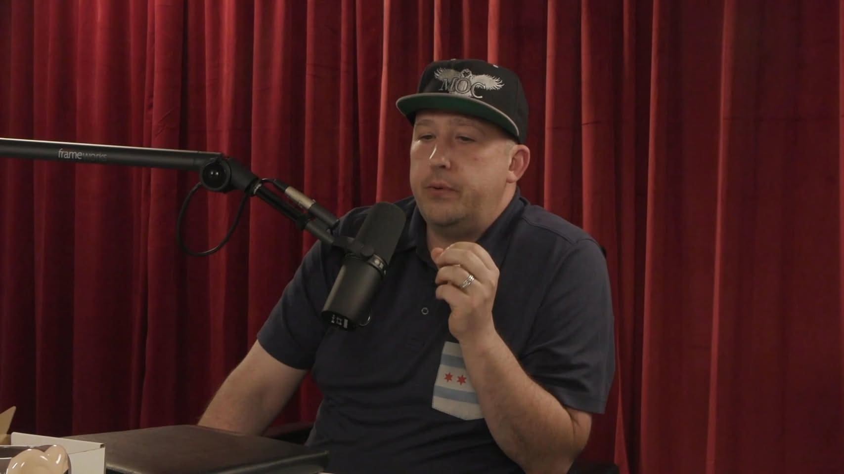 A man in black shirt and hat sitting at table.