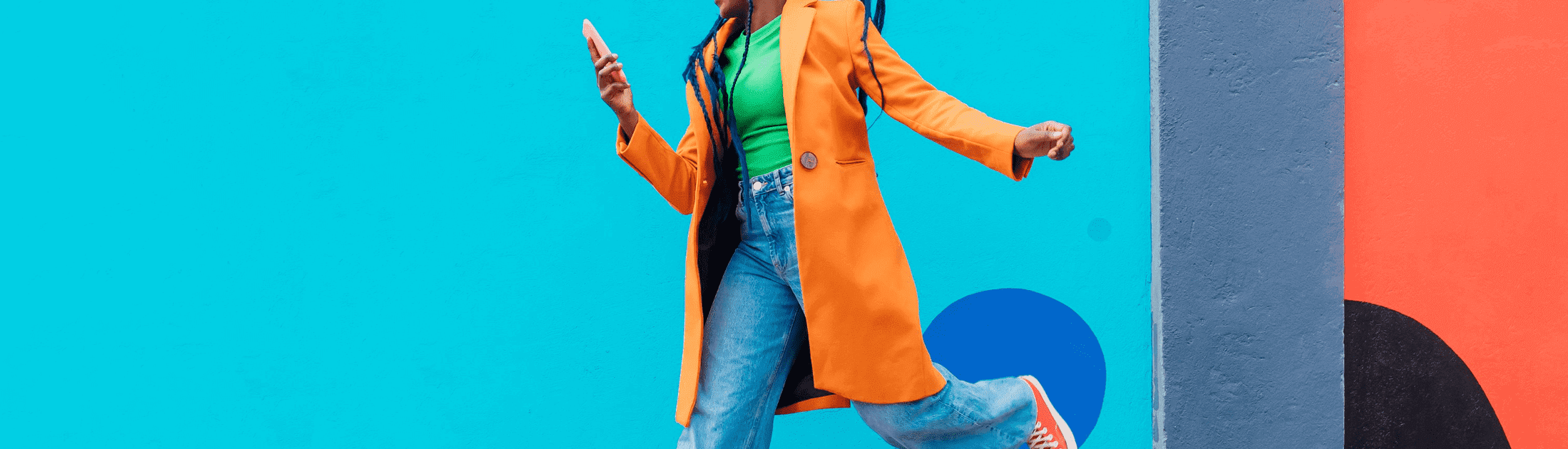 Woman jumping against colorful mural background.