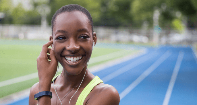 Smiling woman with headphones on track.