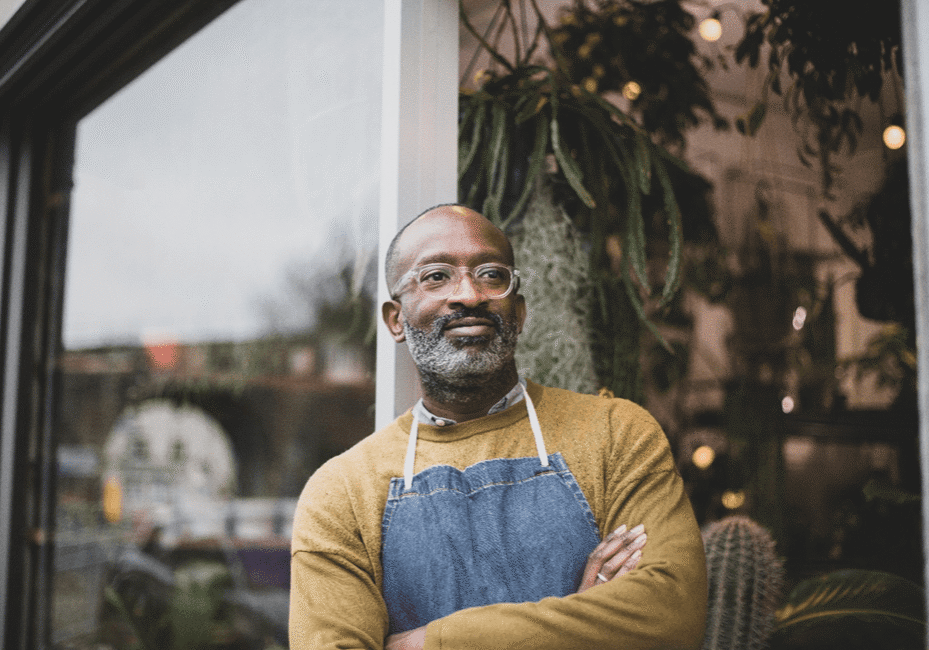A man with an apron standing in front of a window.