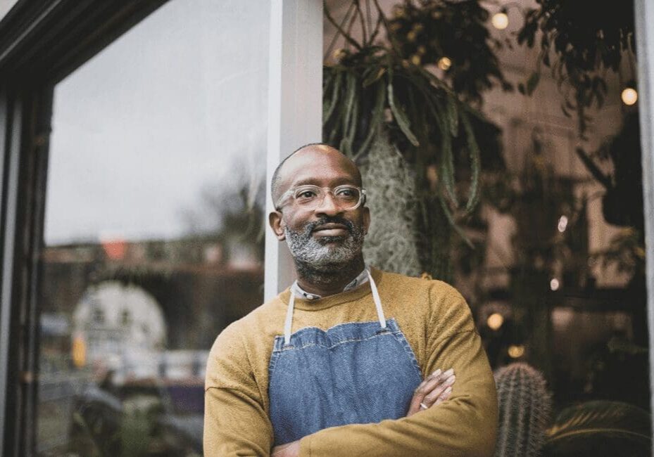A man with an apron standing in front of a window.