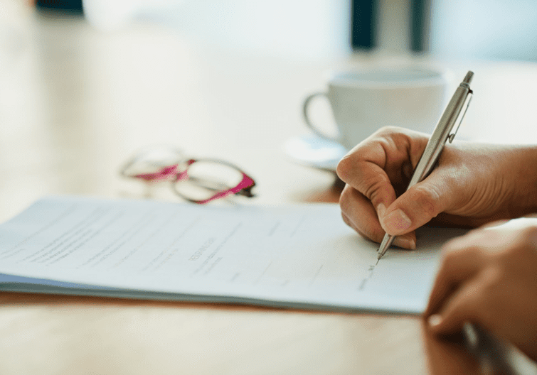 A person writing on paper with a pen.