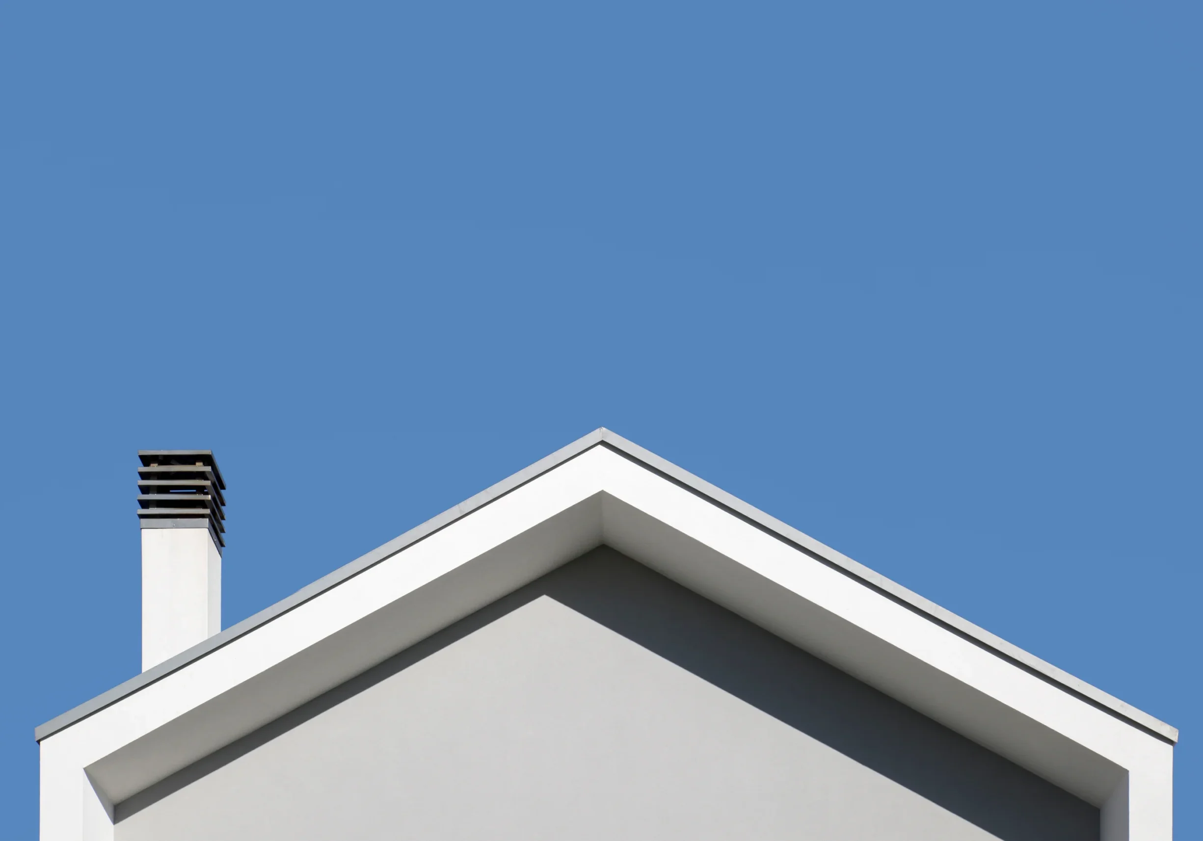 A white roof with a chimney and a blue sky
