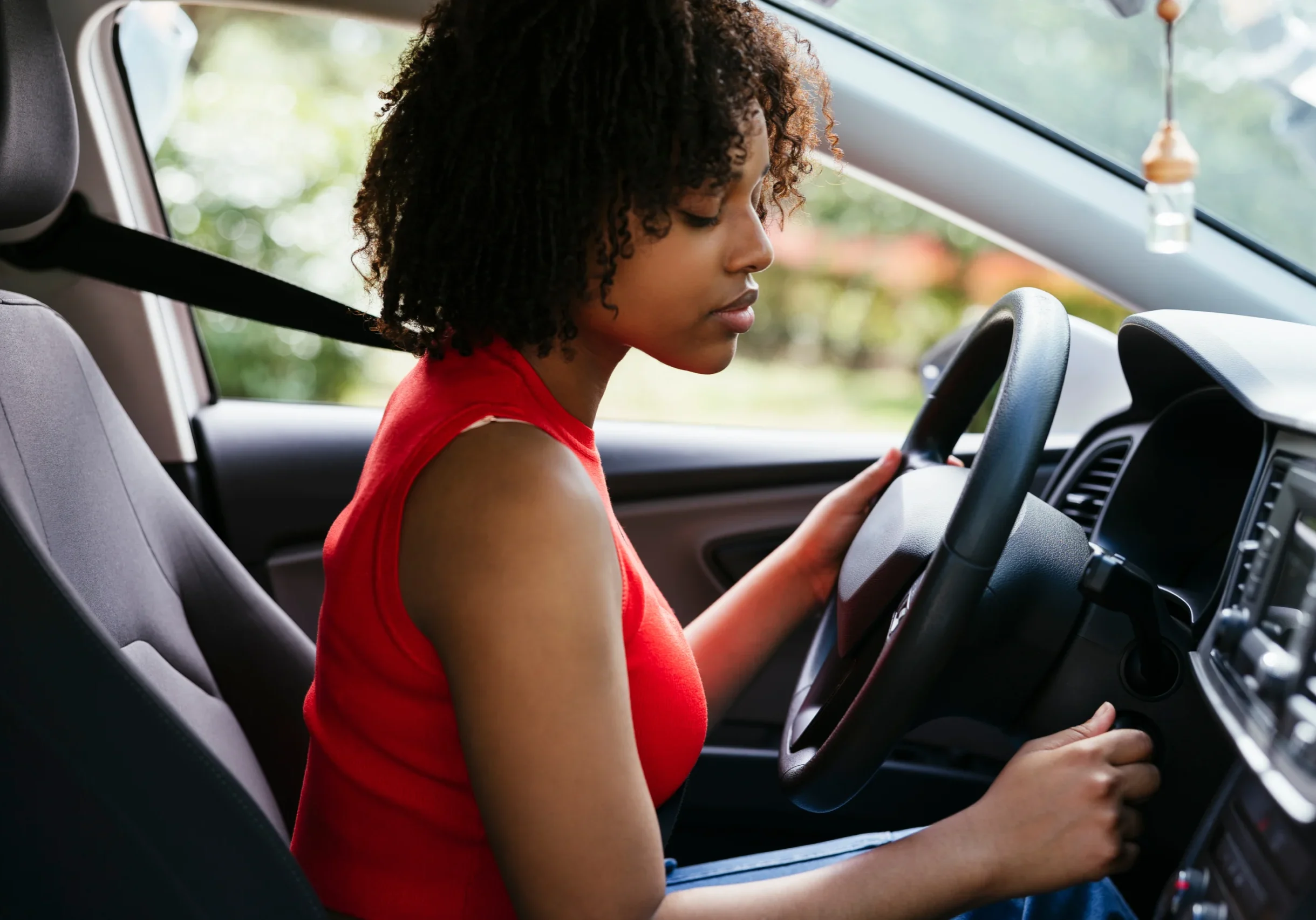 A woman sitting in the driver 's seat of her car.