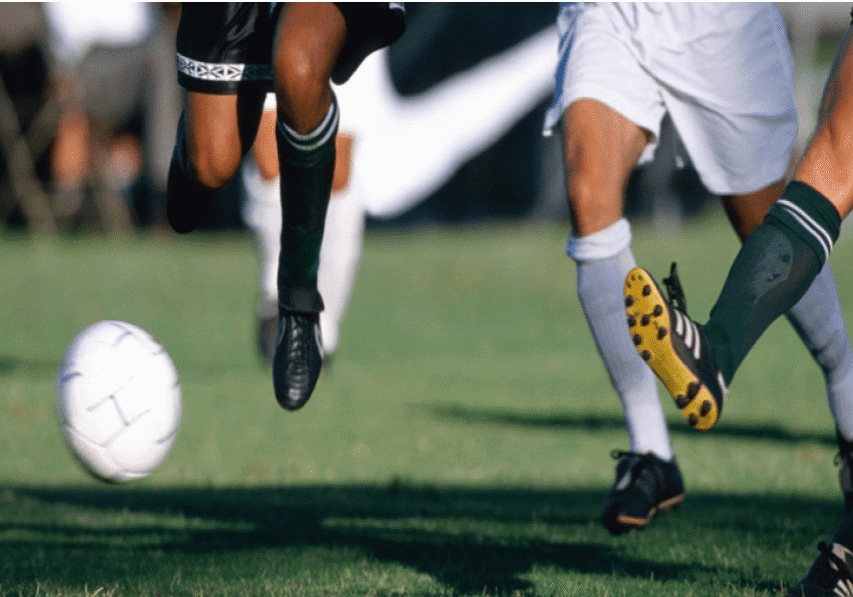 A group of people kicking around a soccer ball.